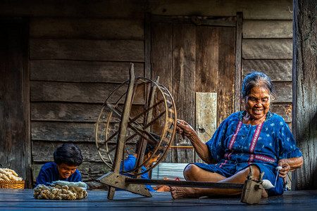 社区中的老年妇女正在将棉花推向编织异图片