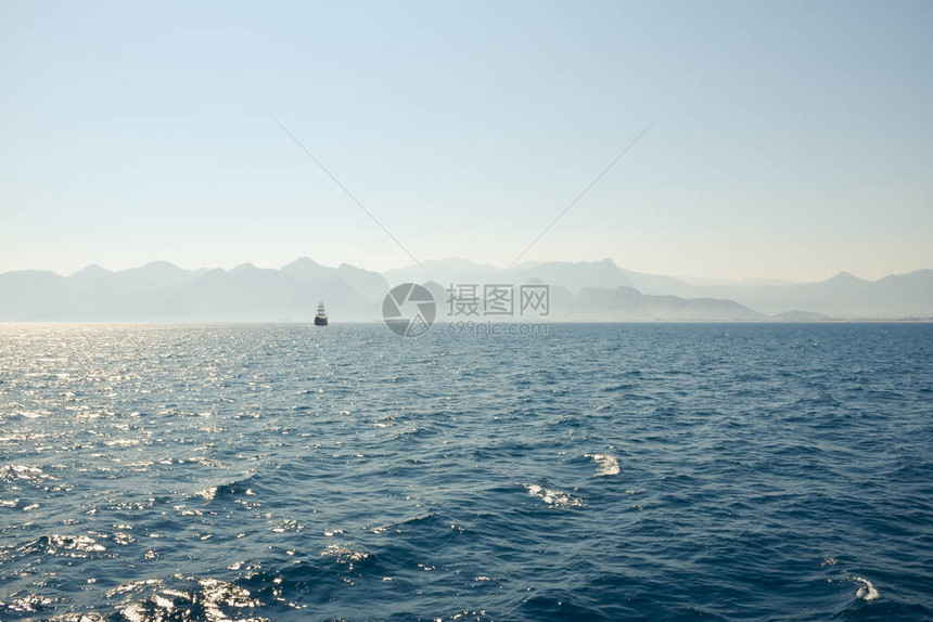 海远处有一艘船航行土耳其安塔利亚附近的海岸在蓝天和山脉的背景下安塔利亚图片