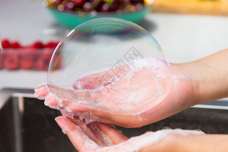 近亲女手握着一个大肥皂泡在没有焦点的厨房水槽上卫生图片