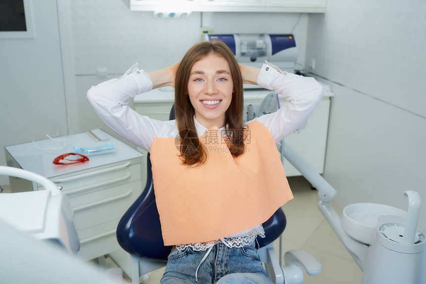 一个快乐的年轻女子在牙科椅上放松图片