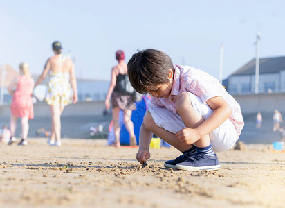 孤独的小男孩独自在沙滩上玩耍的肖像图片