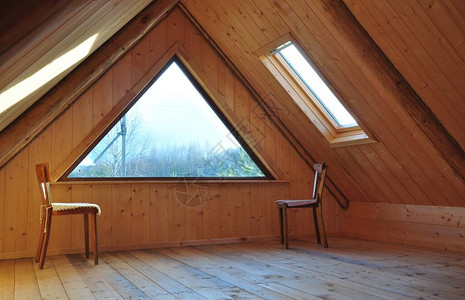 二楼屋顶下的木质内饰带有三角形窗户和天窗图片