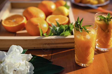 薄荷叶和冰块水晶玻璃杯中的橙汁新鲜的柑橘汁和橙子在桌子上夏季游园会后院聚会时间果汁作背景图片