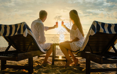日落时在海滩上喝鸡尾酒在热带度假或度蜜月图片