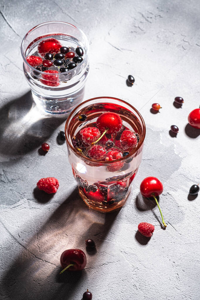 在石混凝土背景上用两个红色透明玻璃杯夏季饮食料角视图图片