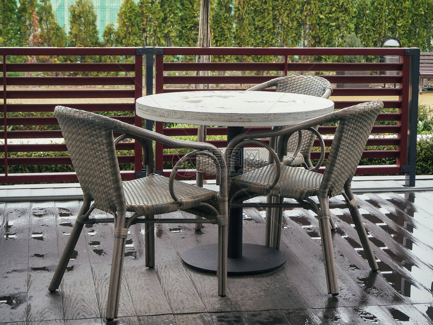 Wicker椅子站在街咖啡厅湿木地板上的圆桌旁图片
