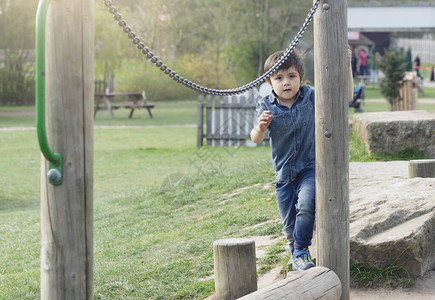 活跃的孩子在公园的木梁上玩平衡图片