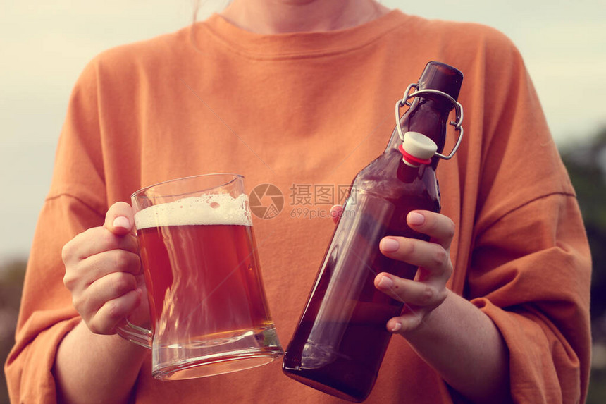 用一杯深色精酿啤酒和一个深色玻璃啤酒瓶与户外喇叭塞特写女手BrewingOktoberfest图片