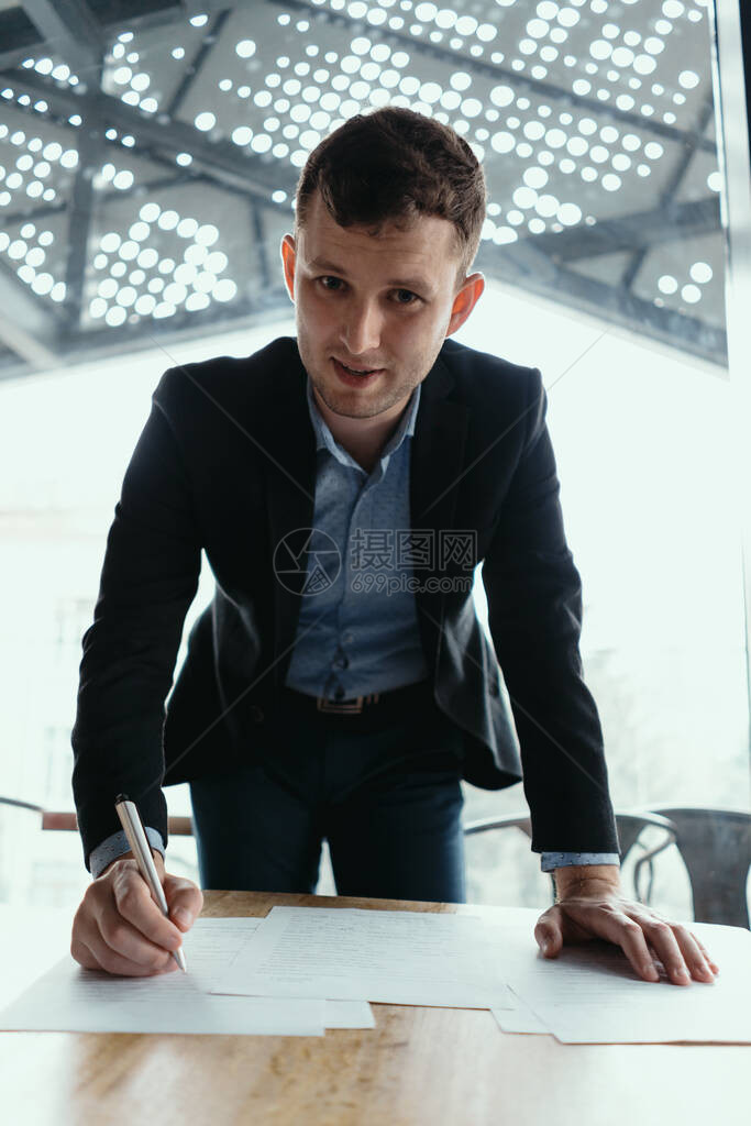 自信的年轻商人在一个现代办公室签署文件图片