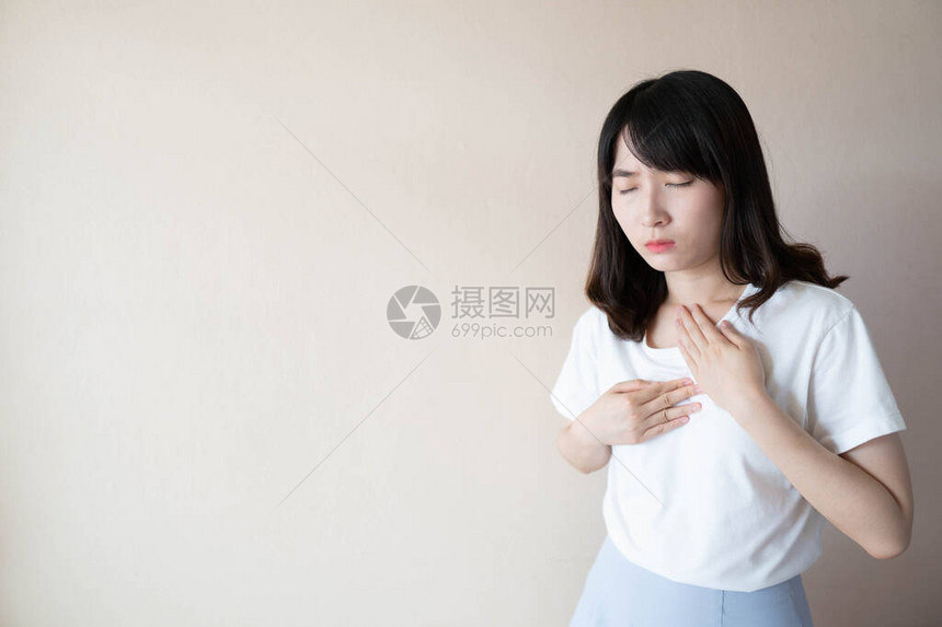 酸反流或胃食管反流病GERD的概念年轻的亚洲女在白色背景下患有胃灼热或胸部不适症状保图片