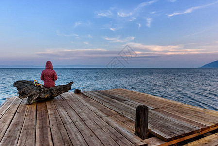 一个人坐在湖边的贝加尔湖上和在日落中挥舞图片