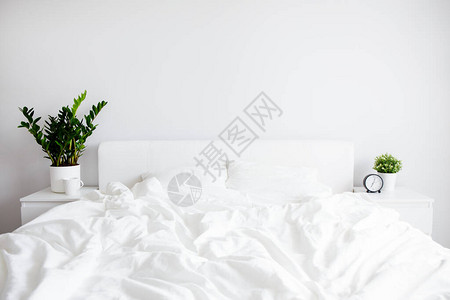 带白毯子和两个枕头有闹钟的床边桌以及家或宾馆图片