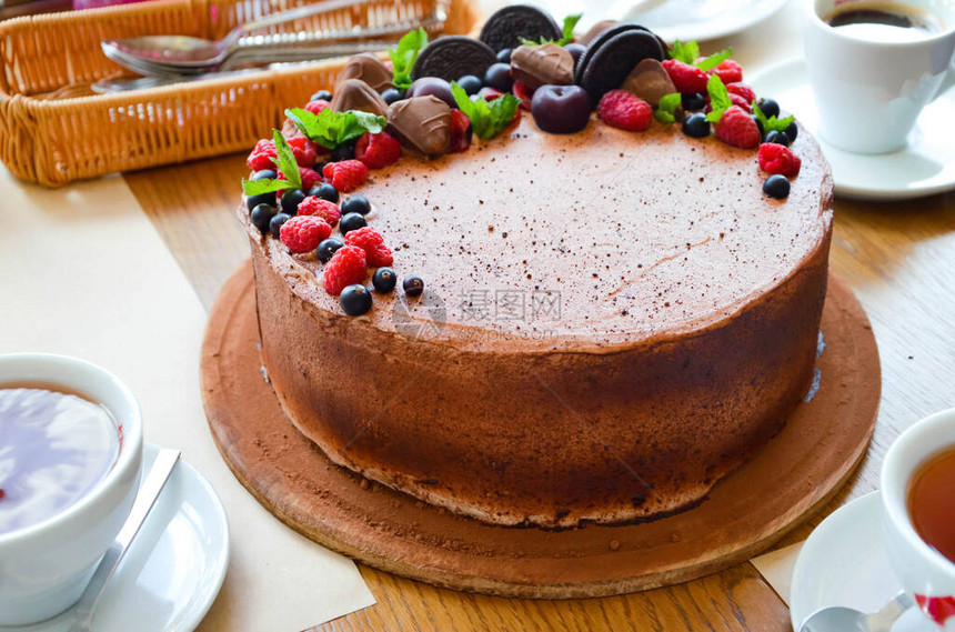 巧克力蛋糕从上面的浆果覆盆子黑醋栗饼干糖果放在桌子上的圆盘上图片