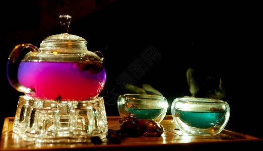 传统茶壶配有美丽的紫色和绿色杯子照亮的图片