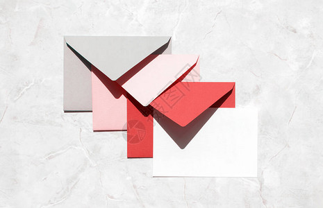 灰色粉红色红色信封和空白的纸卡堆放在大理石图片