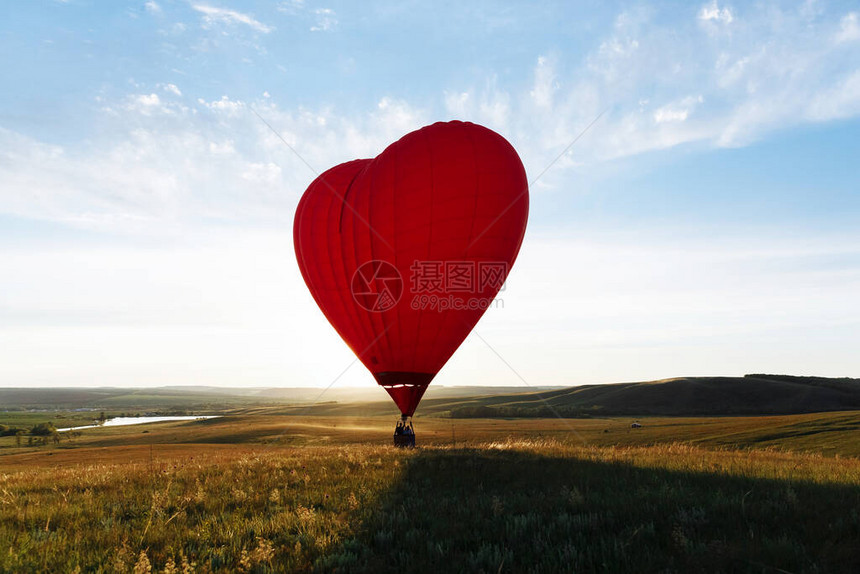 红热气球心形在山谷着陆或起飞图片