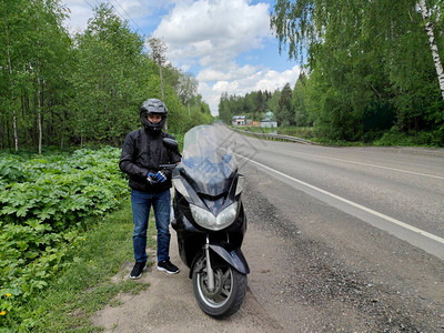 一名年轻的摩托车手戴着黑色防护头盔和夹克图片