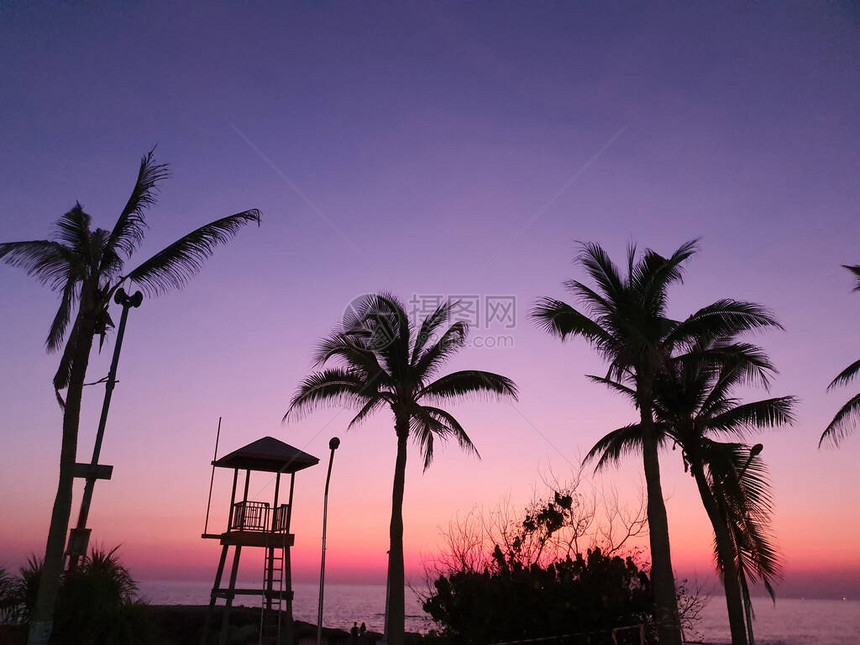 高楼救生塔的轮椅椰子树和灯柱再次在日落时傍晚海边的橙色和印图片