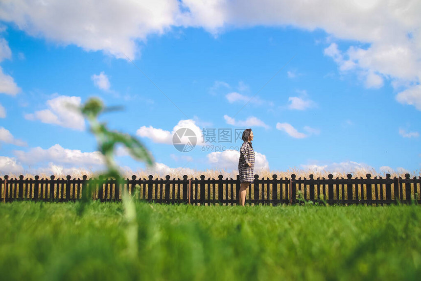 快乐的少女站在青云天空下的绿地上与木图片