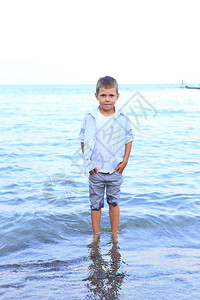 美丽的男孩在夏天站在海岸上一个孩子在岸边的图片