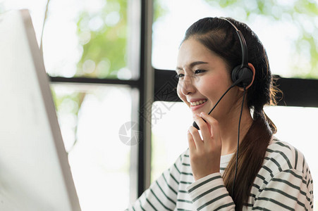 年轻的商业亚洲女工作呼叫中心客户服务代理办公室里有电脑和耳机的商务女图片