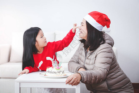 母亲和小女儿在圣诞节吹生日蛋糕家里人快乐图片