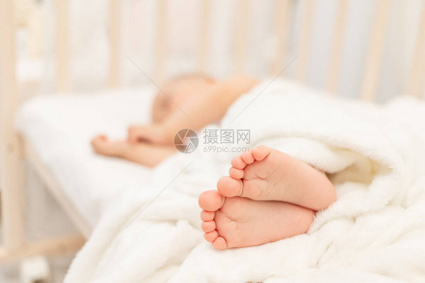 婴儿的腿在一张白色床上熟睡的婴儿的背景下成为焦点图片