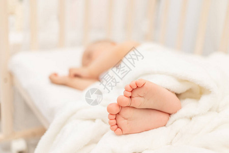 婴儿的腿在一张白色床上熟睡的婴儿的背景下成为焦点高清图片