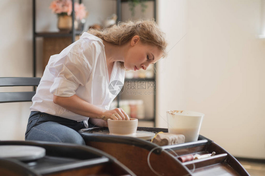 妇女手在陶轮上工作和制作陶罐的特写视图双手从陶罐中雕刻出一个杯子陶图片