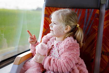 可爱的蹒跚学步的小女孩坐在火车上图片
