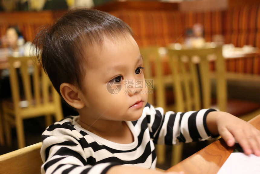 一个亚洲男孩专心地坐着等待食物图片