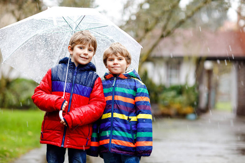 两个小男孩在去学校的路上在雨夹雪雨雪中行走图片