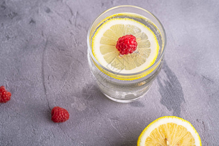 新鲜的冷苏打水饮料加柠檬石质混凝土背景玻璃中的覆盆子水果夏季饮食图片