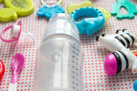 餐桌上粉红色模式背景的婴儿附件勺子和空奶瓶供喂奶调味玩具图片