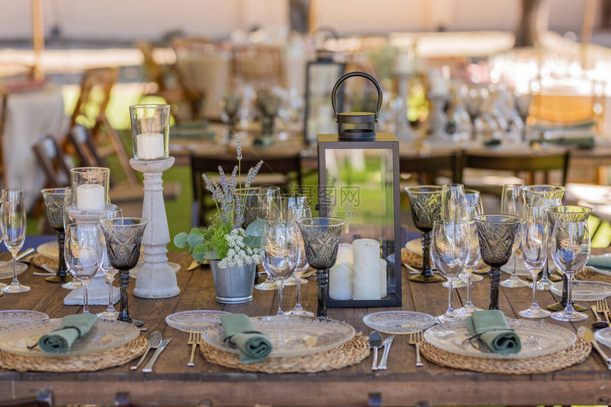 带盘子的户外木桌面纱装饰绿色调杯子餐巾和餐具图片
