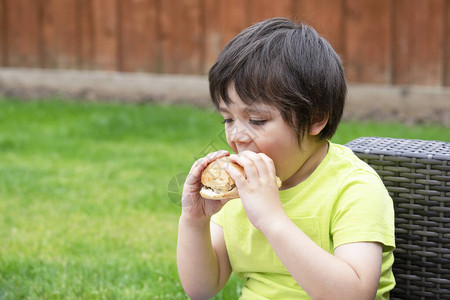 可爱快乐的学龄前孩子坐在花园里吃汉堡包健康的孩子在夏日户外吃美图片