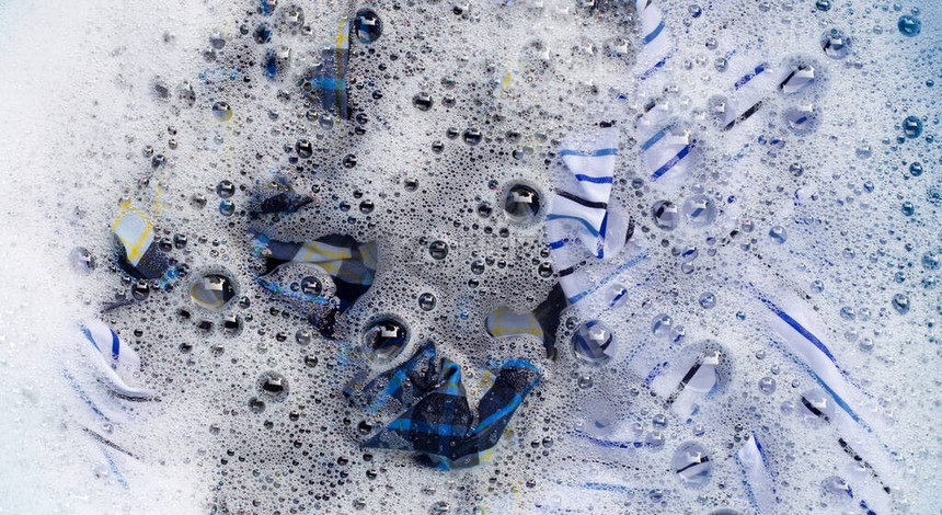 衣服浸泡在粉末洗涤剂水溶解中的顶部视图洗衣概念图片
