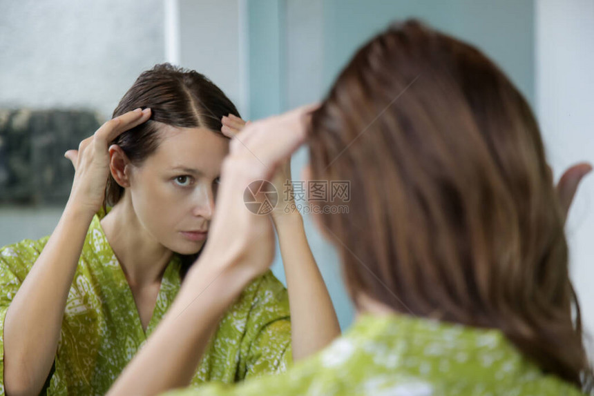 一位漂亮年轻女子在镜子前检查头皮和头发根颜色白发脱发或头皮干图片