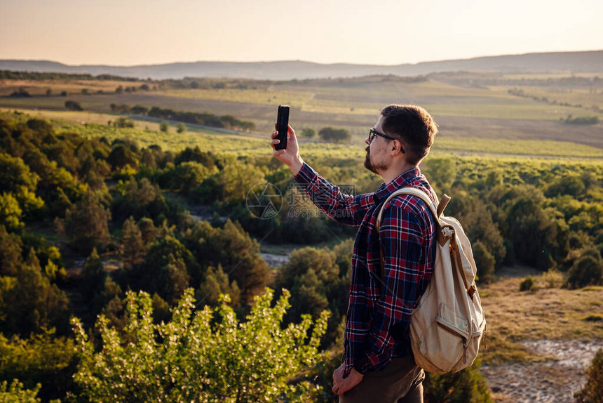 的徒步旅行者用手机拍摄美丽的山景沟通理念在徒步旅行到达目的地时使用图片