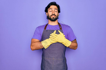 年轻英俊的西班牙裔清洁工穿着家务围裙和洗手套图片