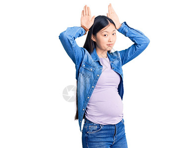 年轻漂亮的女人怀孕期待婴儿做兔子耳朵的手势图片