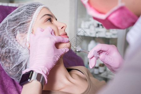 美容科医生在诊所里对一名妇女进行注射手术背景图片