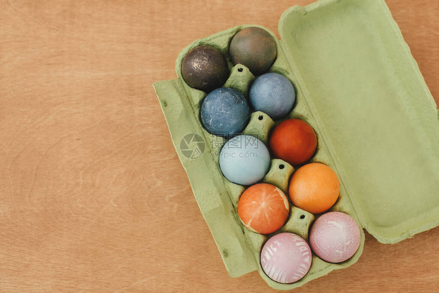 天然染料复活节彩蛋放在木桌平躺的纸箱托盘中图片