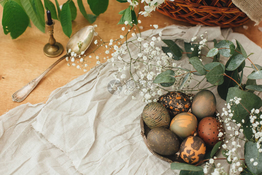 现代复活节彩蛋与春天的花朵和桉树在质朴的木桌上图片
