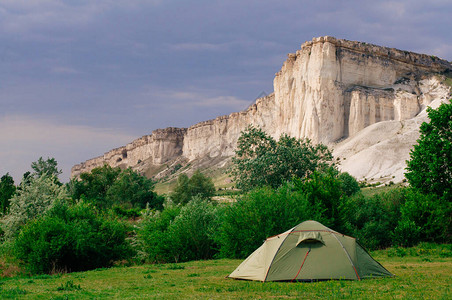 夏日草原上的旅游帐篷在石灰岩山悬崖前图片