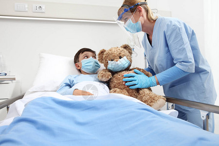 护士照顾在医院床上与泰迪熊玩耍的病人儿童图片