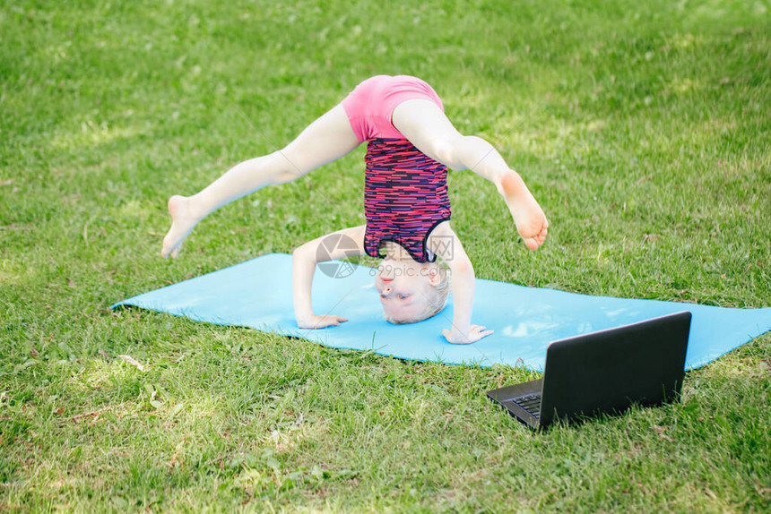 女孩子在网上做户外运动锻炼在公园的互联网上伸展视频瑜伽孩子在后院用笔记本电脑学习健身体操新常态冠状病图片