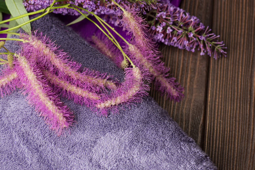 木制背景上的浴巾紫色毛巾和鲜花图片
