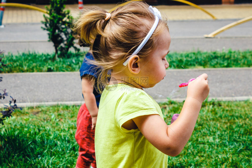 儿童夏季户外活动一个身穿绿色T恤的金发小女孩在一所房子的院子里图片