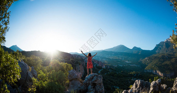 一个穿裙子的女孩站在山顶上图片
